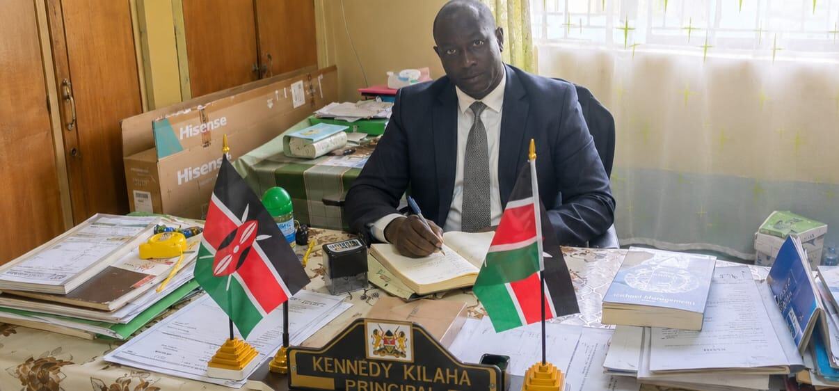 Principal Mr. Kennedy Kilaha at his office desk at Mwibale Senior School