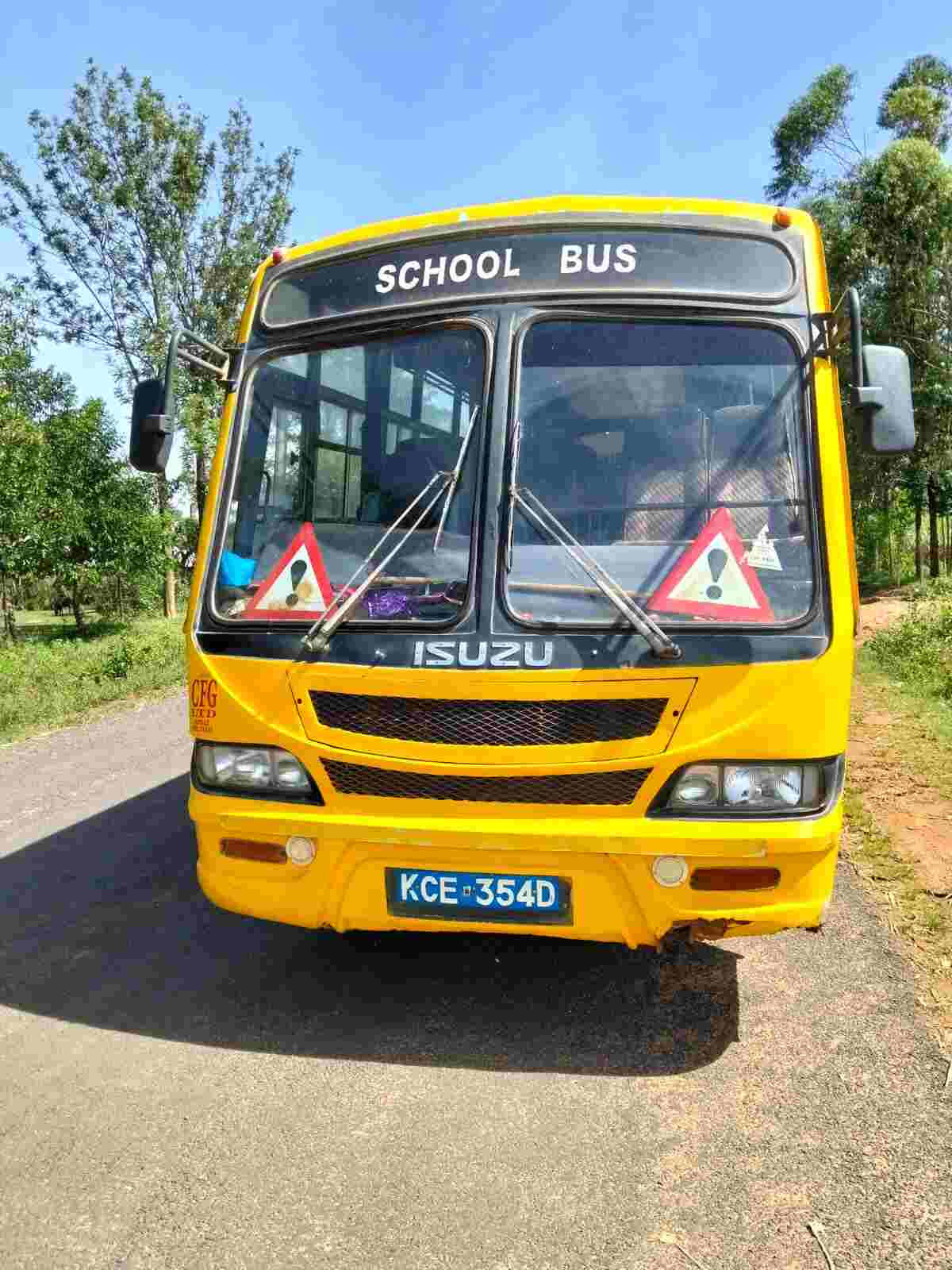 Yellow Isuzu school bus front view at Mwibale Senior School, branded in black